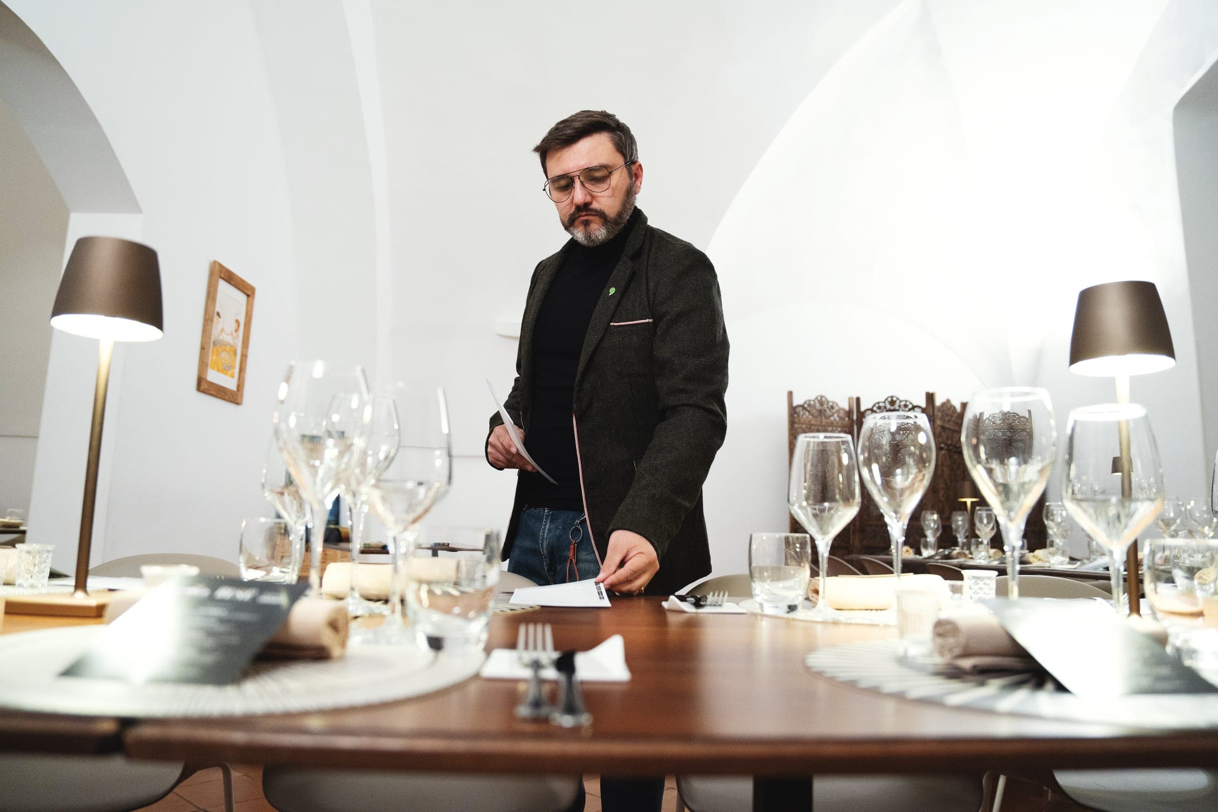 Matteo Contino, Sommelier dell'Olio EVO, in piedi accanto al tavolo apparecchiato con i calici per la degustazione
