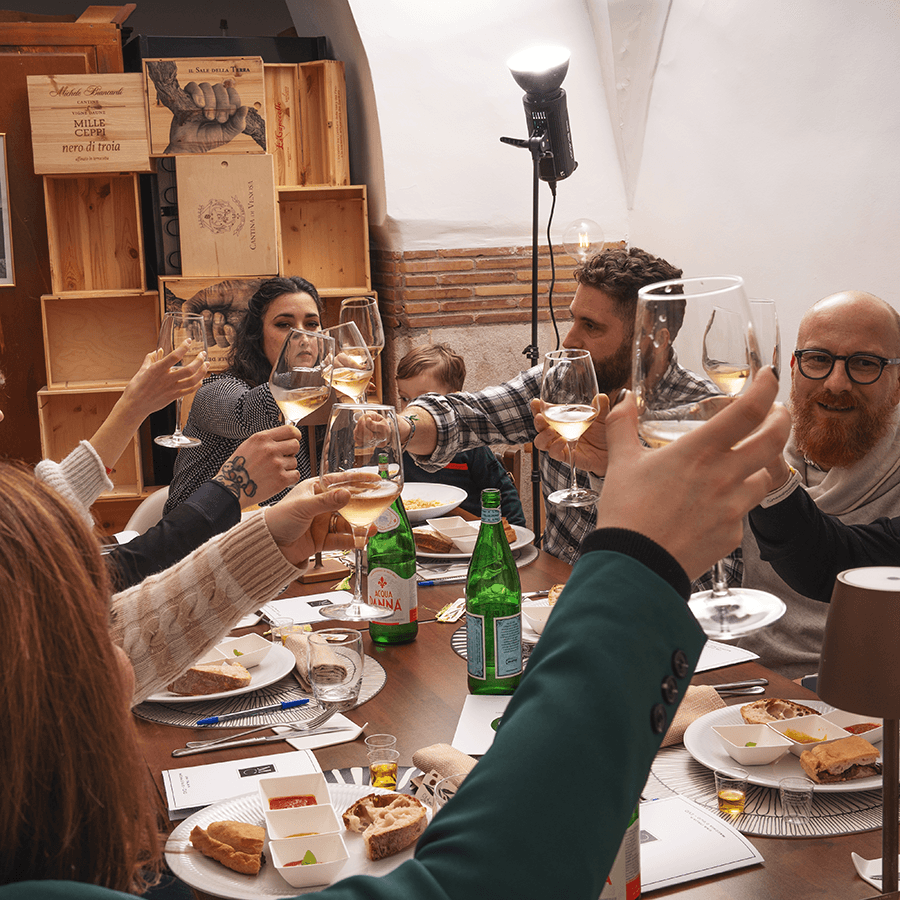 Gli ospiti brindano con i calici attorno al tavolo da Mistella Vino Pizza e Cucina