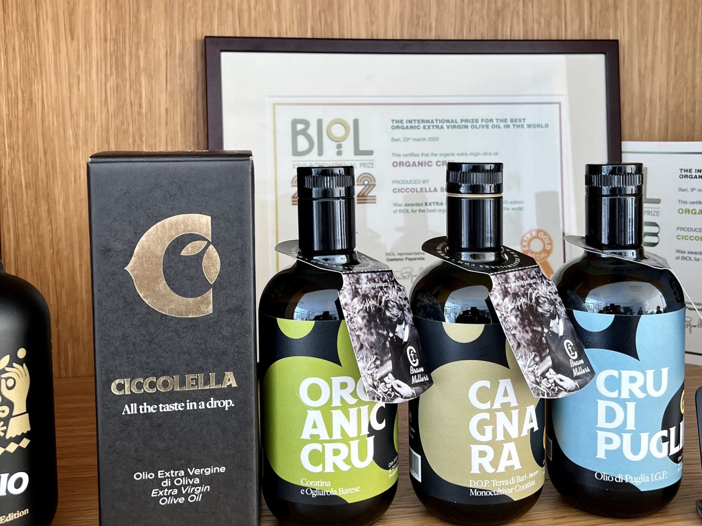 Le bottiglie Organic Cru, Cagnara e Cru di Puglia accanto a una scatola nera Ciccolella e a un diploma incorniciato