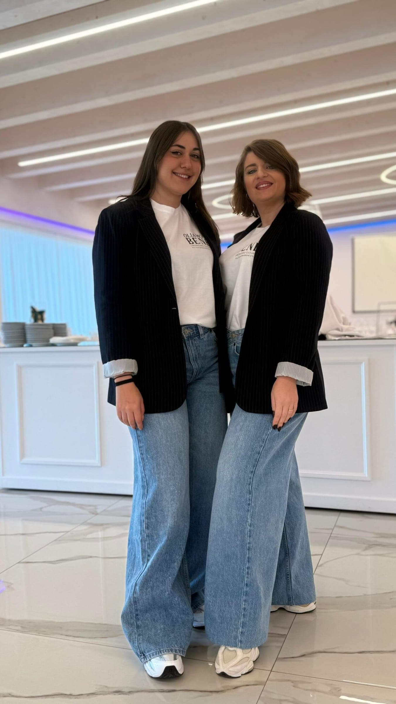 Due persone del team della Sartoria Narrativa in posa, in giacca nera e jeans